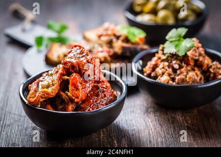 Sun dried tomato with olive oil as antipasto with tapenade and bruschetta in background Stock Photo