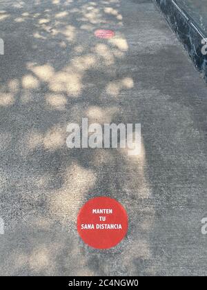 Vertical shot of a red keep distance sign on a concrete floor Stock Photo