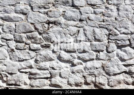 Old grey white weathered rough stone wall texture background Stock Photo