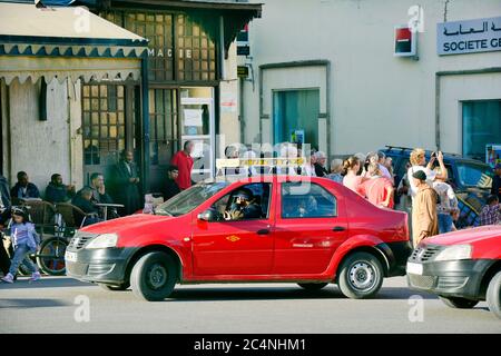 Fes, Morocco - November 20th 2014: Unidentified people and red Petit Taxi - a traditional mode of transport up to four persons, every city had another Stock Photo