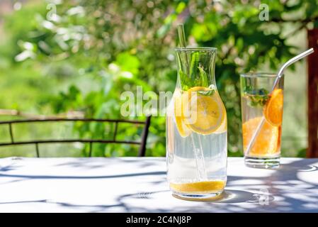 Detox water or lemonade with slices of lemon and basil in glass carafe with recyclable straw. Summertime concept.  Stock Photo