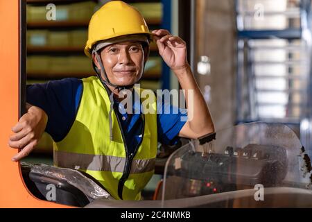 Portrait asian male warehouse worker using forklift truckin large warehouse distribution center. Business warehouse storage transportation and logisti Stock Photo