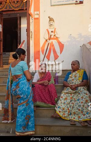 Three elderly, sari-clad Hindu women having a neighborly chat in front of a temple at Banganga Tank, Walkeshwar, Mumbai, India Stock Photo