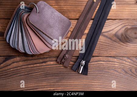 Leather samples for shoes and zipper on dark wooden table. Designer furniture clothes. Stock Photo