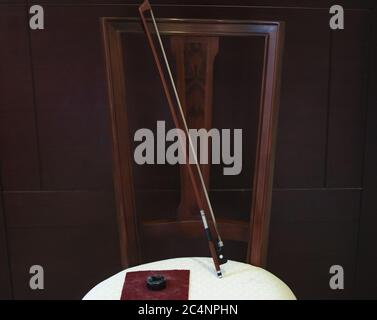 Bow and rosin for the bow of a cello placed on a chair with a dark background Stock Photo