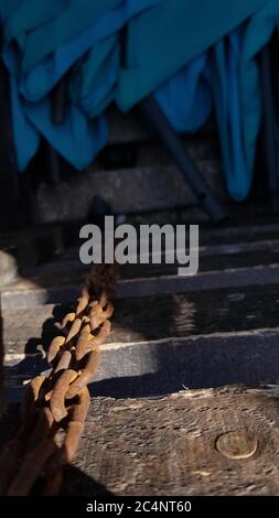 Selective focus to old rusty metal chains in bright sunlight with background in dark shadow. Abstraction of vintage rusty chain links on dark blurred Stock Photo