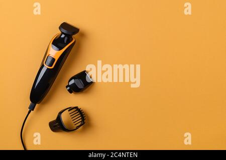 Electric hair clipper or trimmer on a textured yellow background. Barber professional tool for cutting hair. Haircut at the hairdresser or at home. Stock Photo