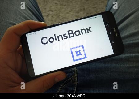 Man holding smartphone with CoinsBank cryptocurrency exchange logo Stock Photo