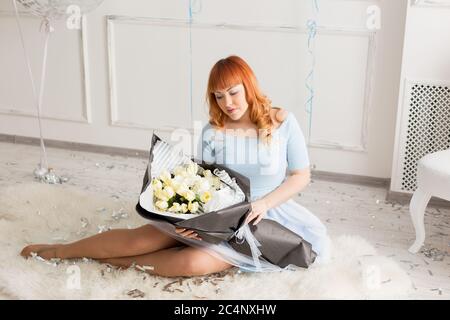 a red-haired girl with a large bouquet of flowers. the girl in the blue dress Stock Photo