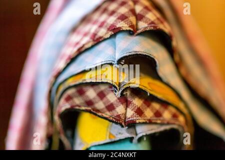 Deluxe fabric masks in production four layer fabric masks laying on top of one another on a green stand on a light wood background close up on masks f Stock Photo