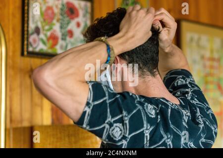 Young male donning deluxe fabric mask side muscular young man in dark patterned shirt on light wood background Stock Photo