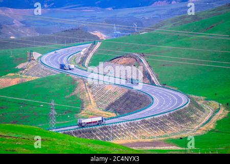 Landscape. Herd of yaks in the green mountain, highway and power towers as background, created in Tibetan Plateau, China Stock Photo