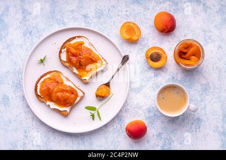 Homemade apricot jam and creme cheese toasts. on blue background. Stock Photo