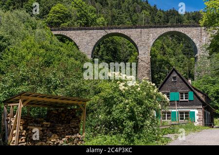 Spectacular view of an old house in front of the old railway bridge at the Ravenna gorge viaduct in Breitnau, Germany Stock Photo