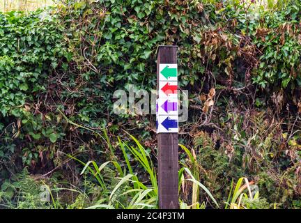 Coloured or Colored hiking route direction arrows on a wooden post Stock Photo