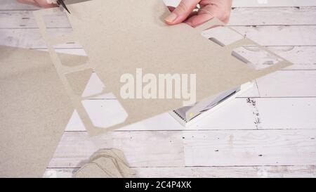 Step by step. Cutting out gift tags from brown paper with a paper punch. Stock Photo