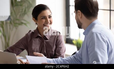 Smiling Indian businesswoman intern listening to mentor at meeting Stock Photo