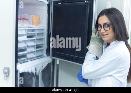 Young Female Research Scientist working with a Cold Nitrogen Liquids in a Laboratory. Genetics and Pharmaceutical Studies and Researches. Smiling into Stock Photo