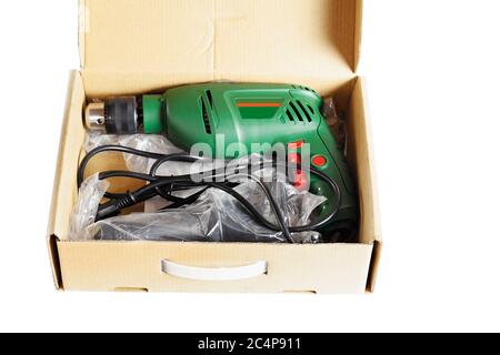 New electric drill in a cardboard box. Close-up. Isolated over white background. Stock Photo