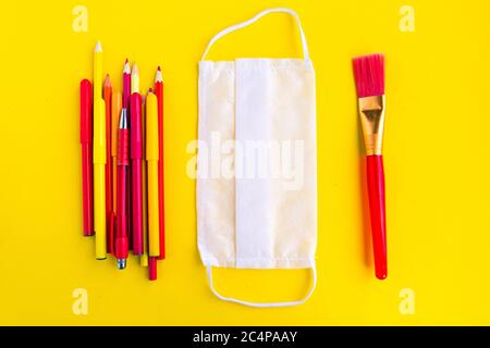 Color pencils and medical mask on yellow background. Back to school concept. School quarantine concept Stock Photo