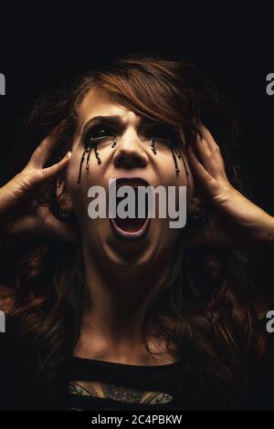 Portrait of a possessed woman, bloody eyes, face expressing suffering and madness Stock Photo