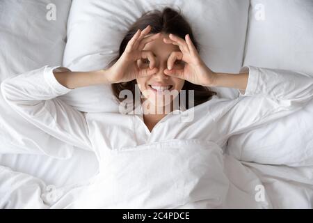 Top view of happy woman make funny gesture in bed Stock Photo
