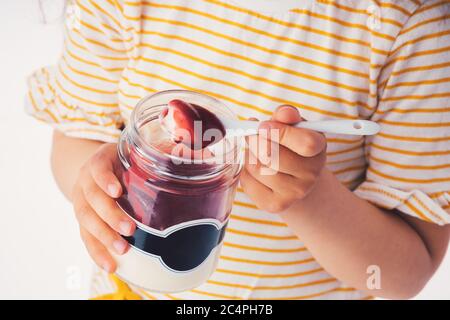 Little girl eat milky dessert with cream and fruity jelly in a jar. Stock Photo