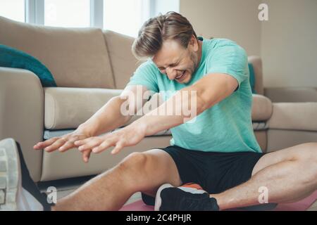 Hard working caucasian man doing fitness exercises on the floor at home Stock Photo