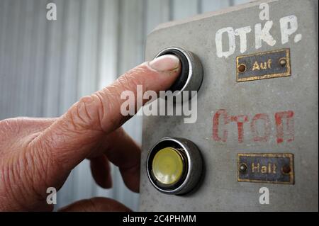 Finger of worker pushing button Open on a control panel Stock Photo