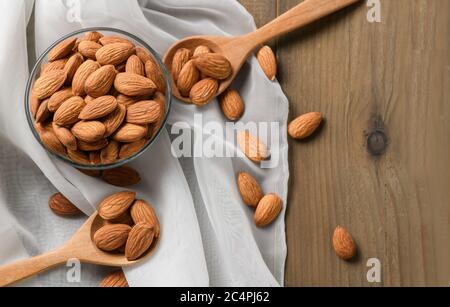 Almonds nuts peeled in glass cup on wood table background. Almonds are very popular nuts and high protein . healthy food. Stock Photo