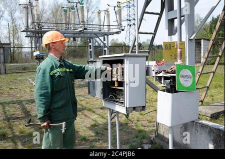 At the power substation. Worker checking connections on the electric board turning start tumbler. Pump station Stock Photo