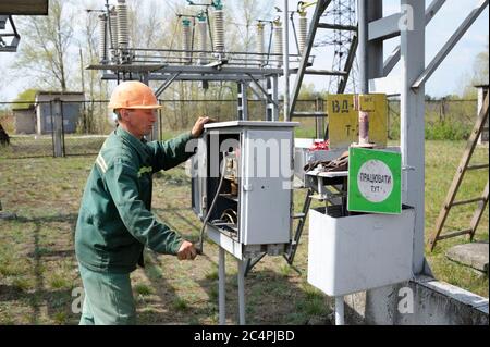 At the power substation. Worker checking connections on the electric board turning start tumbler. Pump station Stock Photo