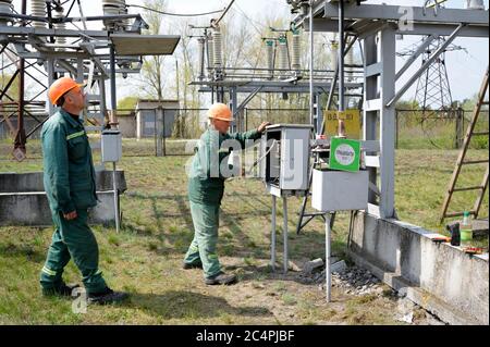 At the power substation. Worker checking connections on the electric board turning start tumbler. Pump station Stock Photo
