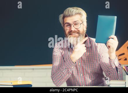 Brutal bearded teacher smiling at camera at back of classroom at the elementary school Stock Photo