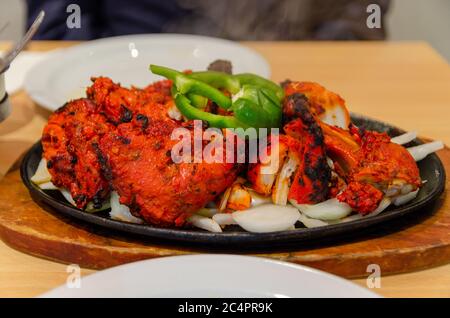 Tandoori Chicken on a sizzler platter with onion and green capsicum Stock Photo