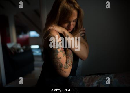 Attractive tattooed woman sitting on bed in the morning Stock Photo