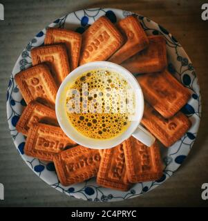 Parle biscuits rounded around a cup of tea with formation of bubbles in it Stock Photo