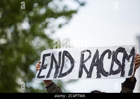 A metal sign up in the air, holding with both hands, 'end racism' black marker, black lives matter rally Stock Photo
