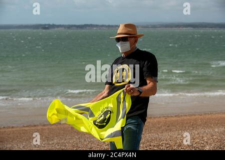 Southsea, Hampshire, England, UK. June 2020.  Man wearing a mask and social distancing t shirt and keep your distance hi vis vest on a windy day on th Stock Photo