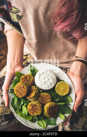 Chickpea Spinach Falafel With Tzatziki Sauce. Girl Holding Plate WIth Healthy Vegetarian Dinner Falafel And Sauce. TOp View Selective Focus. Clean Eat Stock Photo