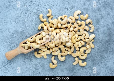 Raw cashew nuts on wooden spoon on concrete background, top view. Paleo food diet Stock Photo