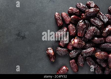 Dried red dates on black slate background, top view copy space. Arabic food, dried fruits, islam religion concept Stock Photo