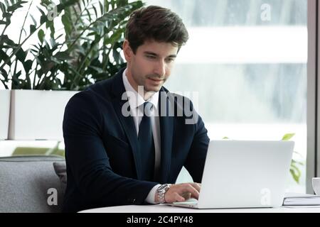 Young successful businessman wearing suit working on laptop typing Stock Photo