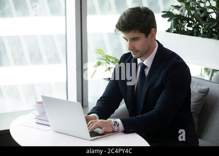 Young business man typing on computer sitting on sofa Stock Photo