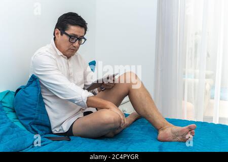 Executive works at home in his bedroom on video conference with his tablet Stock Photo