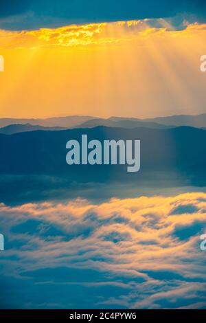 sunrise on the snowy mountains and the sun's rays pass through the clouds Stock Photo