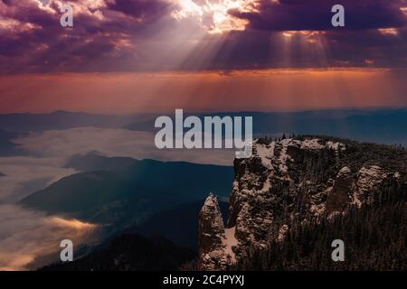 sunrise on the snowy mountains and the sun's rays pass through the clouds Stock Photo