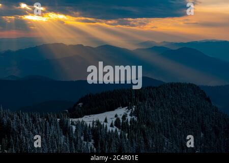 sunrise on the snowy mountains and the sun's rays pass through the clouds Stock Photo
