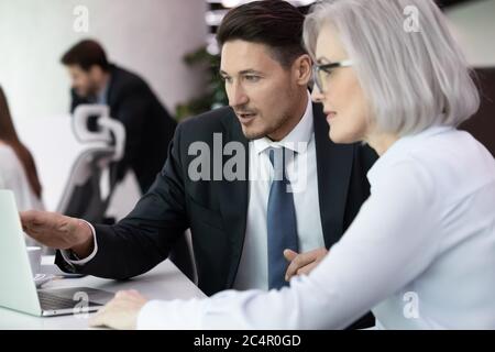 Experienced business man and woman discussing startup ideas using computer Stock Photo