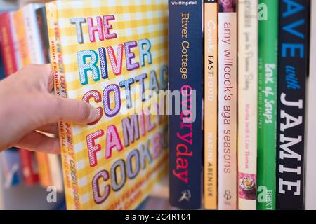 hand taking cookery book from shelf in kitchen - UK Stock Photo